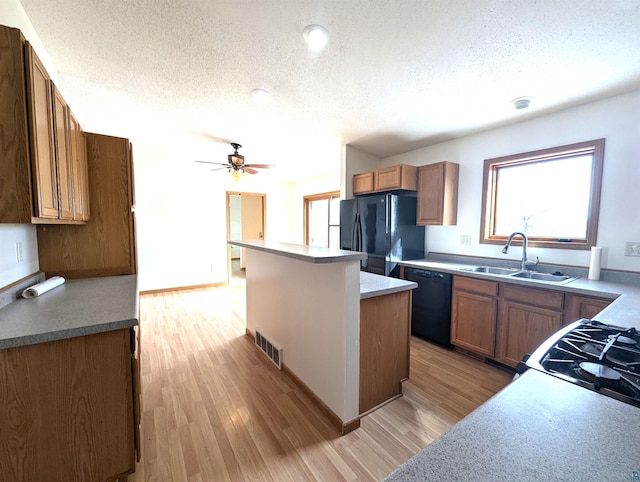 kitchen featuring a wealth of natural light, visible vents, a kitchen island, a sink, and black appliances