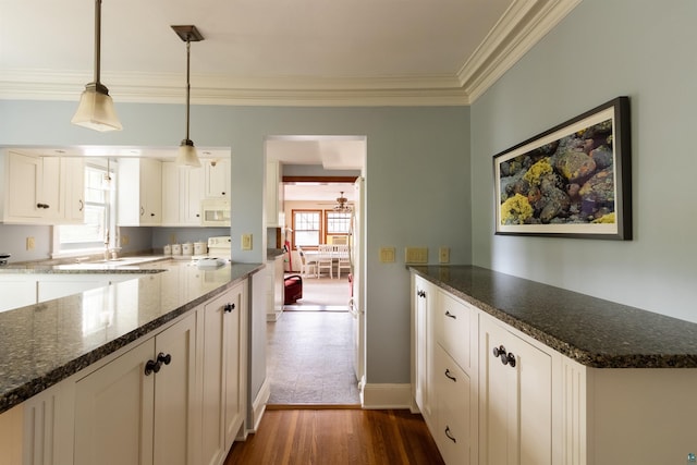 kitchen featuring white cabinets, dark wood finished floors, white microwave, ornamental molding, and pendant lighting