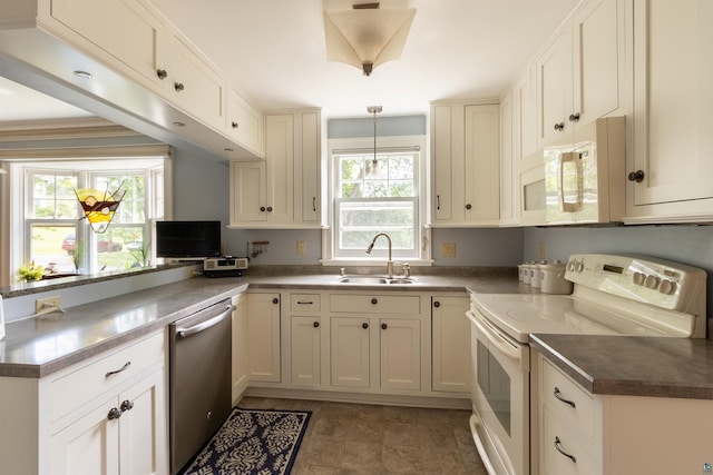 kitchen with a peninsula, white appliances, a sink, white cabinets, and pendant lighting