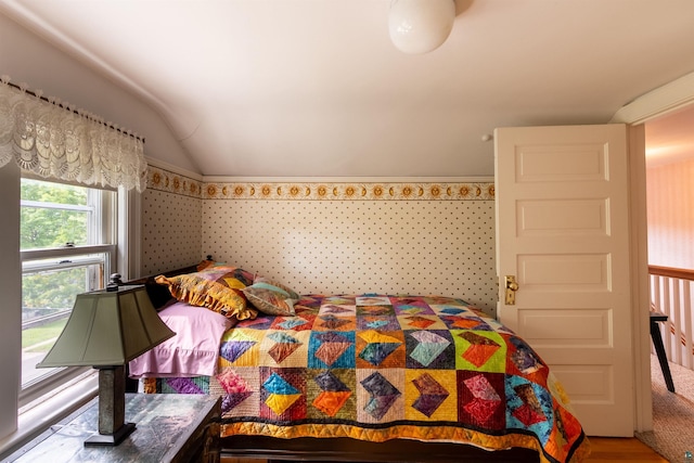 bedroom featuring vaulted ceiling and wallpapered walls