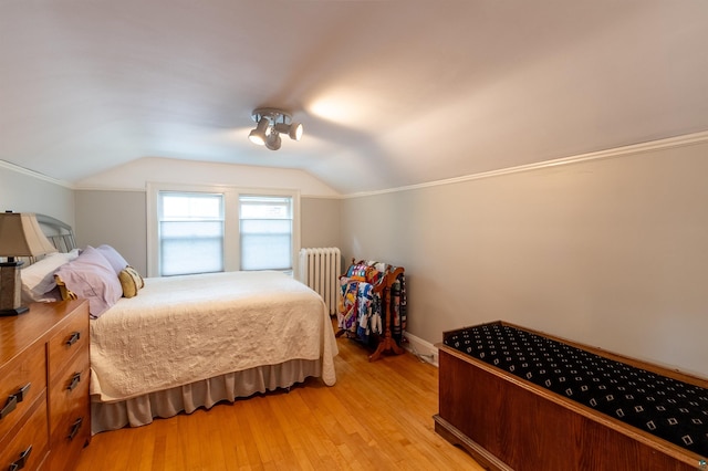 bedroom featuring vaulted ceiling, light wood-style flooring, and radiator