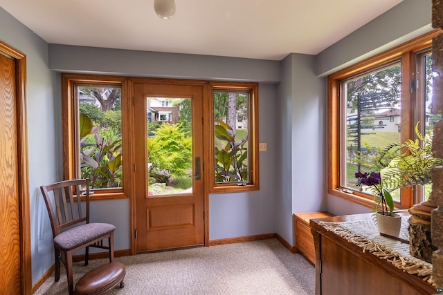 doorway to outside with baseboards and light colored carpet