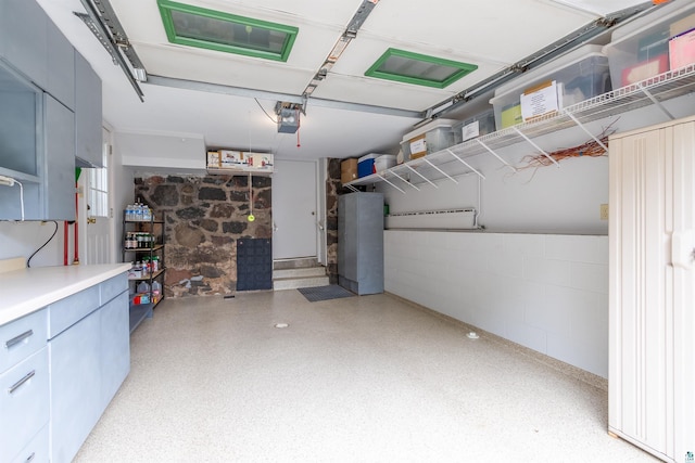 garage featuring concrete block wall and a garage door opener