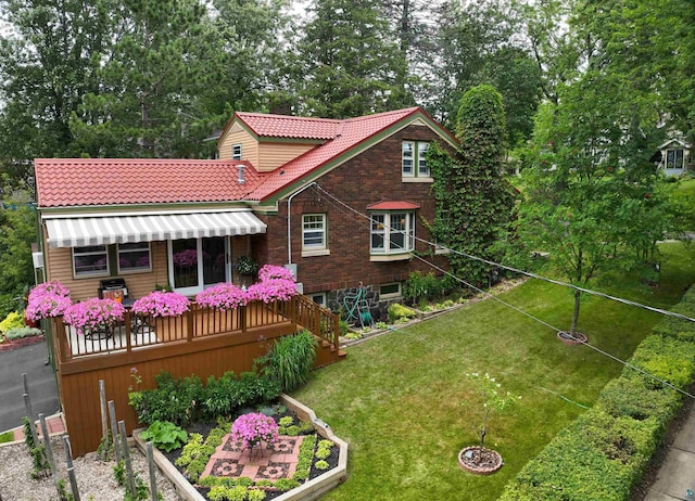 back of house with a yard, a vegetable garden, a tile roof, and brick siding