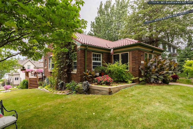 view of front of house featuring a front yard, brick siding, and a tiled roof