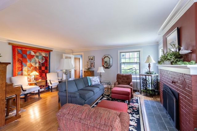 living area featuring radiator, a brick fireplace, crown molding, and wood finished floors