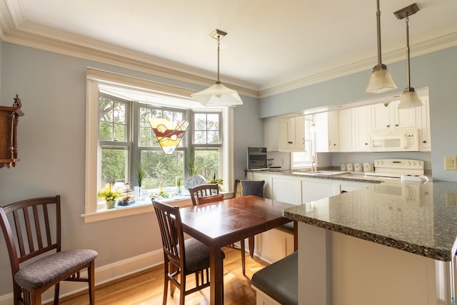 dining space featuring baseboards, crown molding, and light wood finished floors