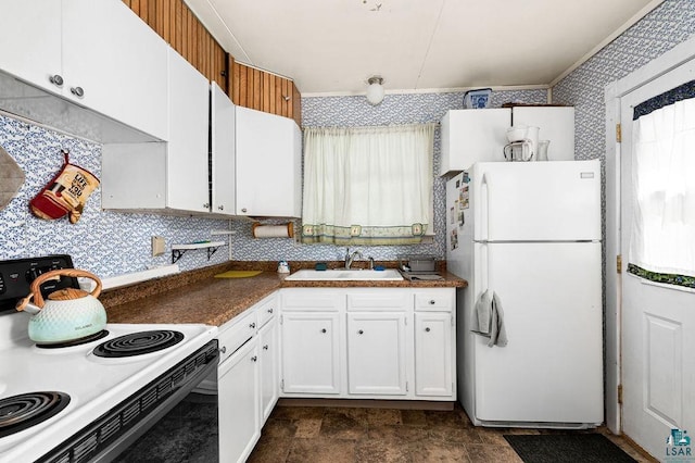 kitchen with wallpapered walls, range with electric cooktop, freestanding refrigerator, white cabinetry, and a sink