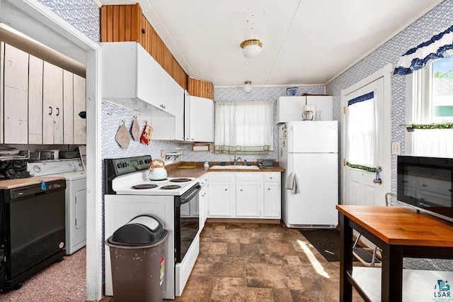 kitchen with electric stove, freestanding refrigerator, stone finish floor, a sink, and washer / dryer