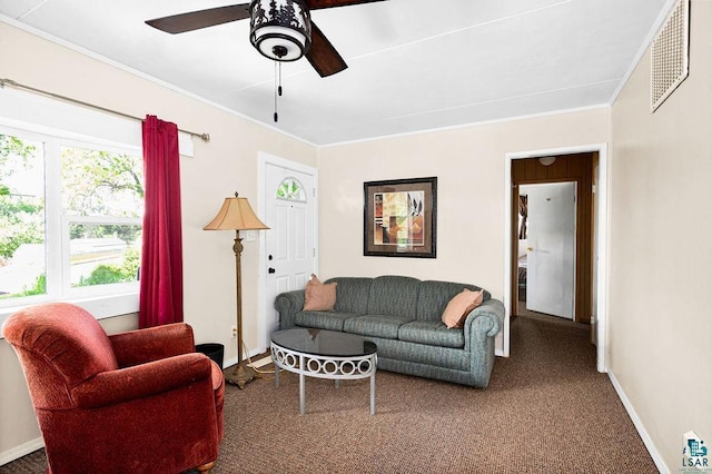 carpeted living area featuring a ceiling fan, visible vents, crown molding, and baseboards