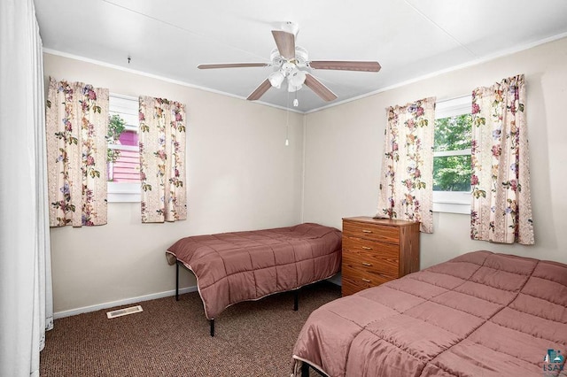 carpeted bedroom with baseboards, multiple windows, visible vents, and crown molding