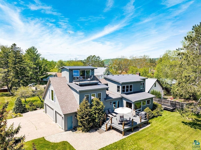 back of property featuring a lawn, a balcony, a chimney, roof with shingles, and fence