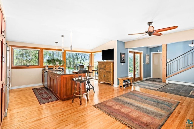 kitchen featuring a breakfast bar area, a baseboard heating unit, brown cabinetry, a sink, and light wood-type flooring