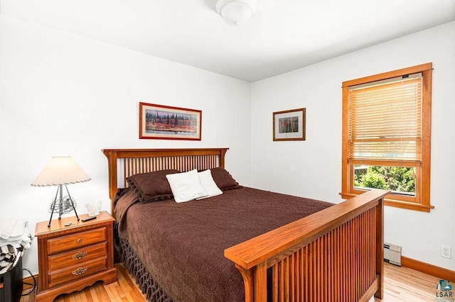 bedroom with light wood finished floors, a baseboard radiator, and baseboards