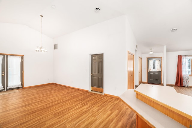 interior space featuring a chandelier, high vaulted ceiling, visible vents, baseboards, and light wood-style floors