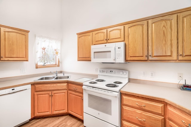 kitchen featuring light wood-type flooring, white appliances, light countertops, and a sink