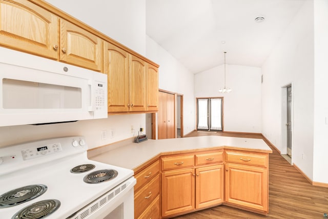 kitchen with light countertops, light wood-style floors, vaulted ceiling, white appliances, and a peninsula