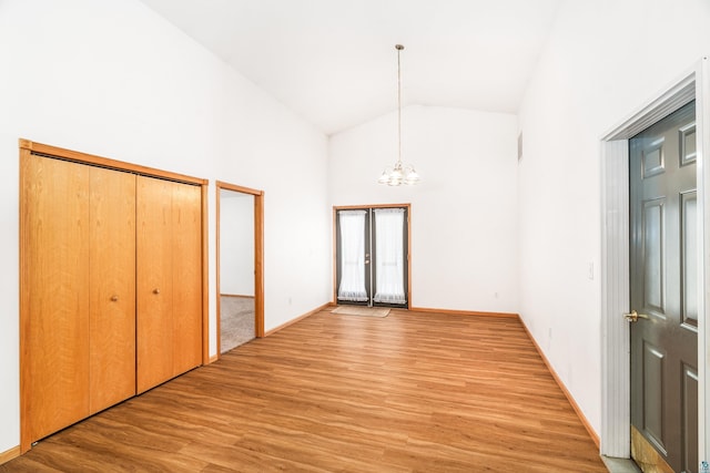 interior space with light wood finished floors, baseboards, a chandelier, and high vaulted ceiling