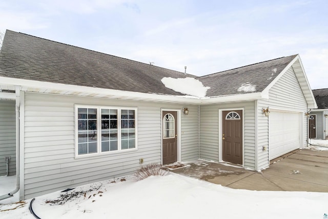 ranch-style home featuring a shingled roof and an attached garage