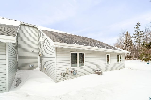 snow covered property with a shingled roof