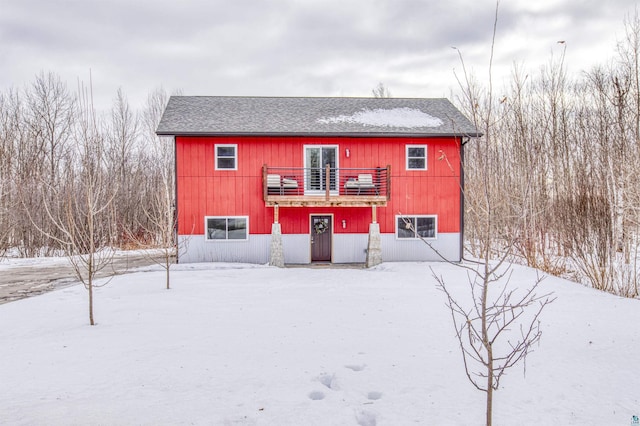 snow covered back of property featuring roof with shingles