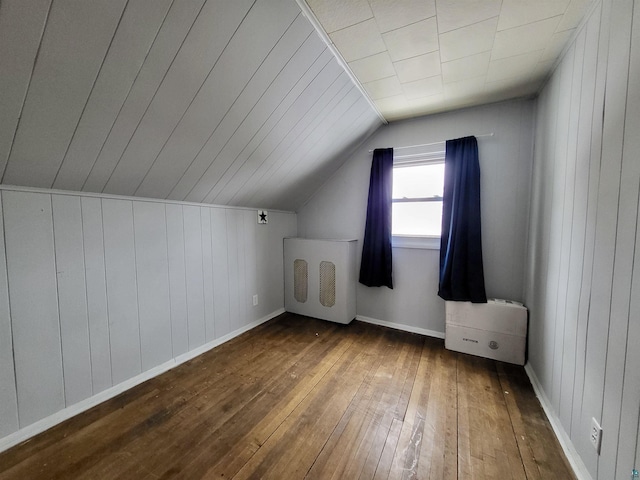 bonus room with lofted ceiling, dark wood-type flooring, wood walls, and baseboards