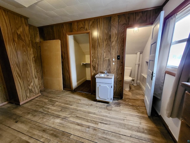 bathroom with toilet, wood walls, plenty of natural light, and hardwood / wood-style flooring