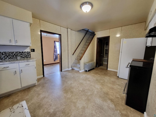 kitchen with radiator, light countertops, electric range oven, white cabinets, and concrete floors