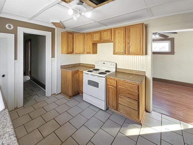 kitchen featuring brown cabinets, baseboards, ceiling fan, and white electric range oven