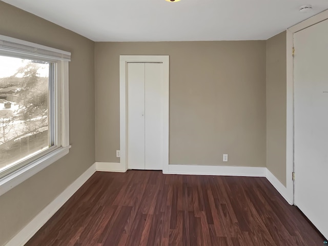 unfurnished bedroom with a closet, baseboards, and wood finished floors