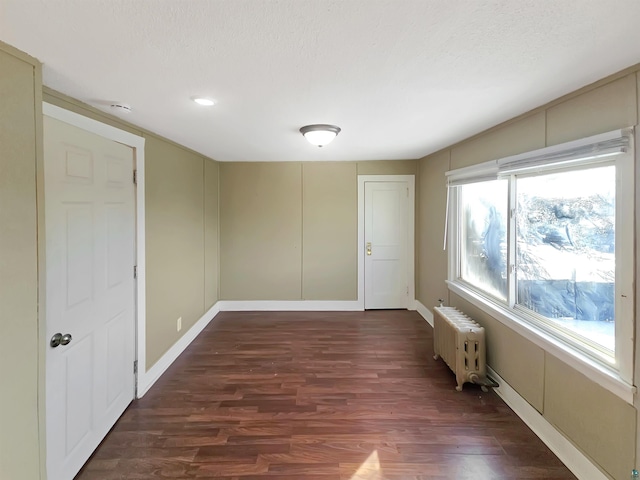 unfurnished room with radiator heating unit, baseboards, dark wood-style flooring, and a textured ceiling