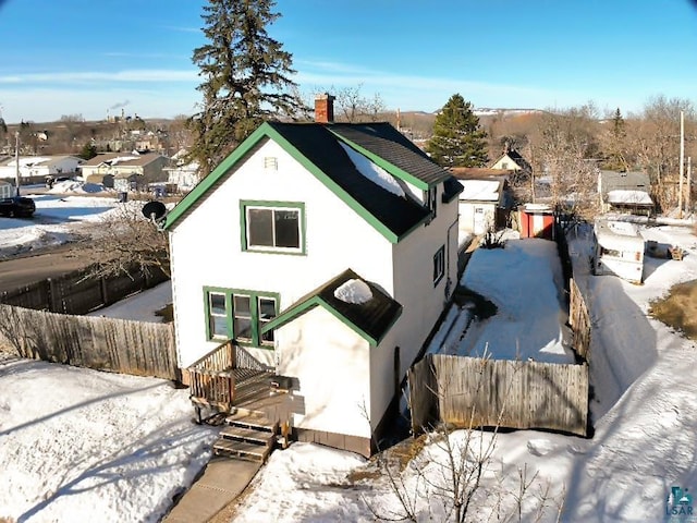 exterior space with stucco siding, a chimney, and fence