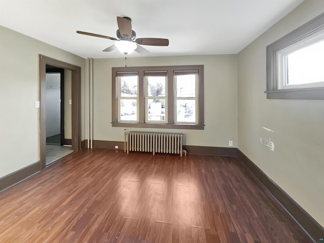 unfurnished room featuring a ceiling fan, radiator heating unit, wood finished floors, and baseboards