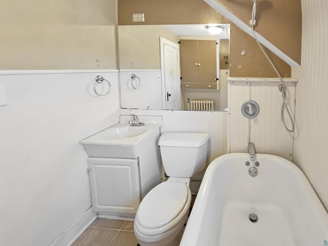 bathroom featuring tile patterned flooring, toilet, a washtub, and wainscoting