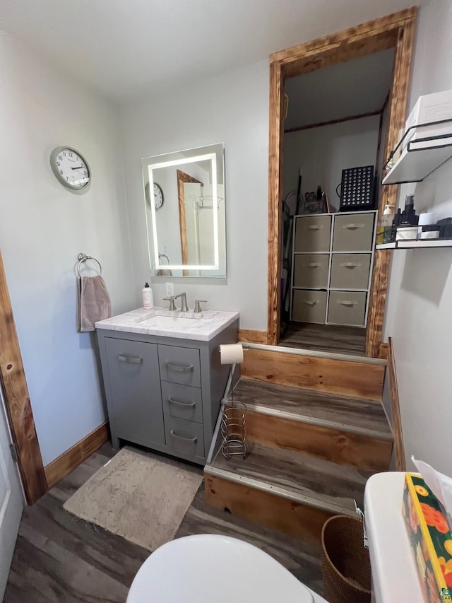 bathroom featuring vanity, toilet, wood finished floors, and baseboards