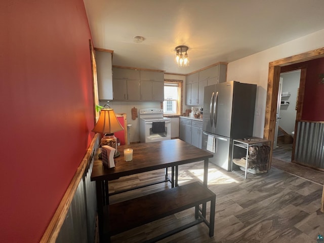 kitchen with gray cabinetry, freestanding refrigerator, an inviting chandelier, wood finished floors, and white electric range