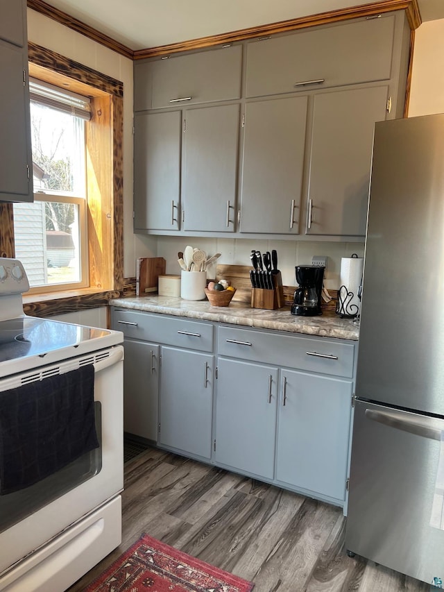 kitchen with gray cabinets, freestanding refrigerator, light countertops, electric stove, and light wood-type flooring