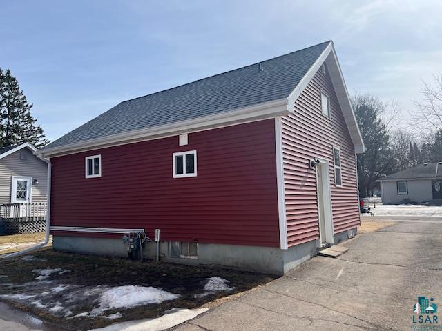 view of property exterior with a shingled roof