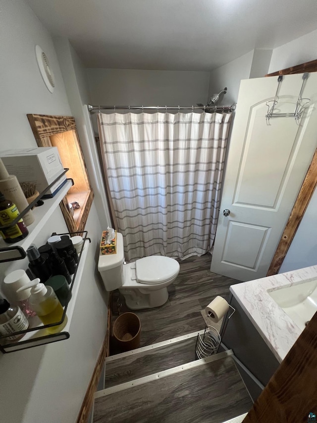 full bathroom with curtained shower, toilet, and wood finished floors