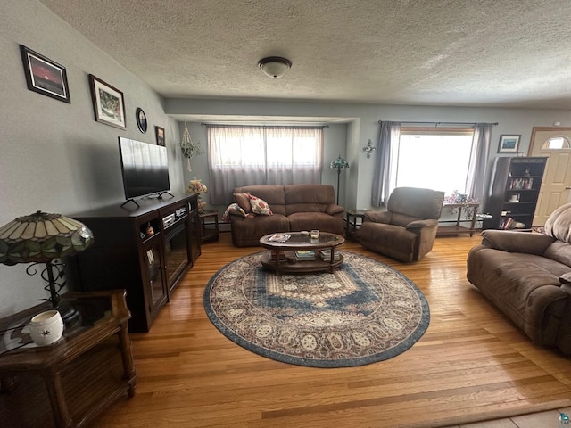 living room with a baseboard radiator, a textured ceiling, and light wood-style flooring