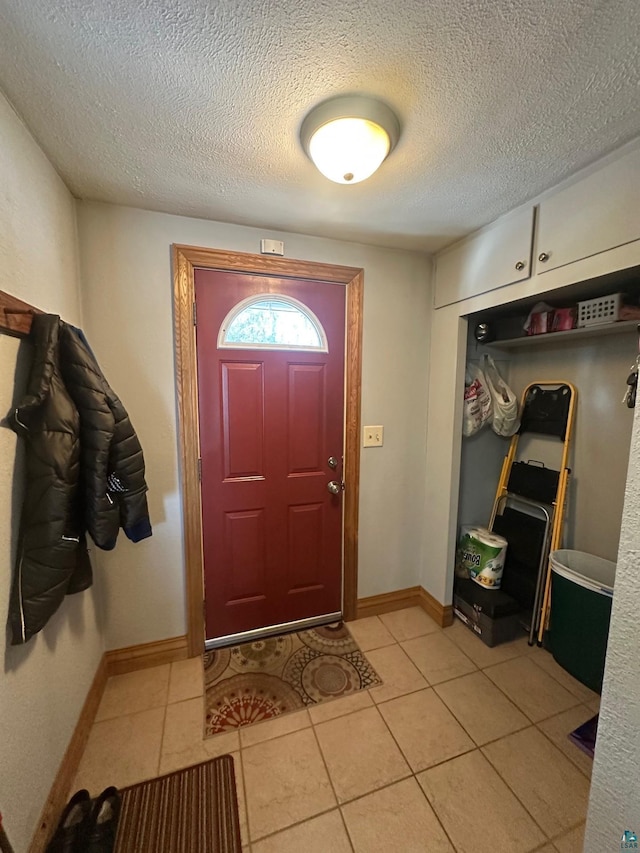 entrance foyer featuring light tile patterned floors, baseboards, and a textured ceiling