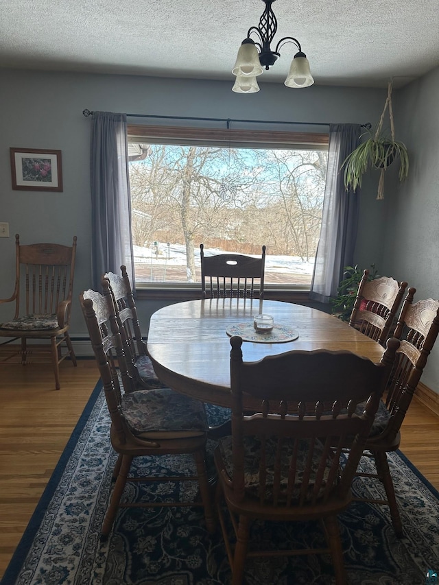 dining room featuring a notable chandelier, wood finished floors, and a textured ceiling