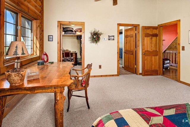 office space with baseboards, carpet, a high ceiling, and a ceiling fan