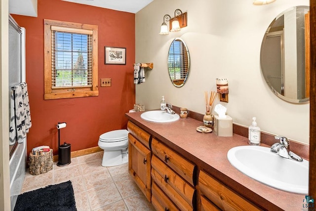 bathroom featuring tile patterned floors, toilet, double vanity, and a sink