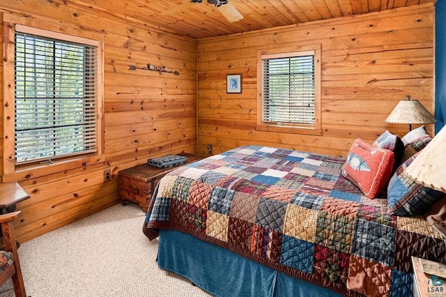 carpeted bedroom with multiple windows, wood ceiling, wood walls, and ceiling fan