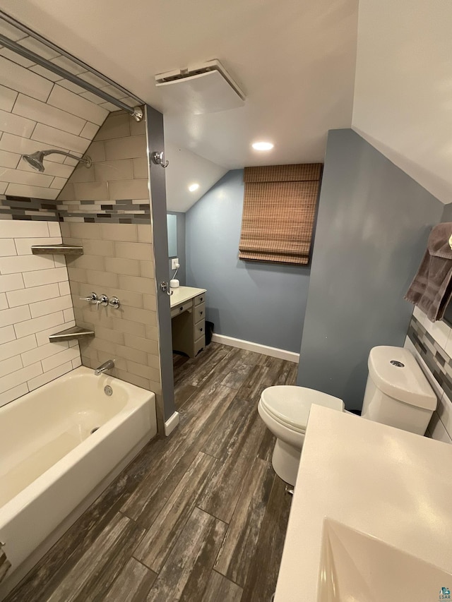 bathroom with toilet, lofted ceiling, wood finished floors, baseboards, and vanity