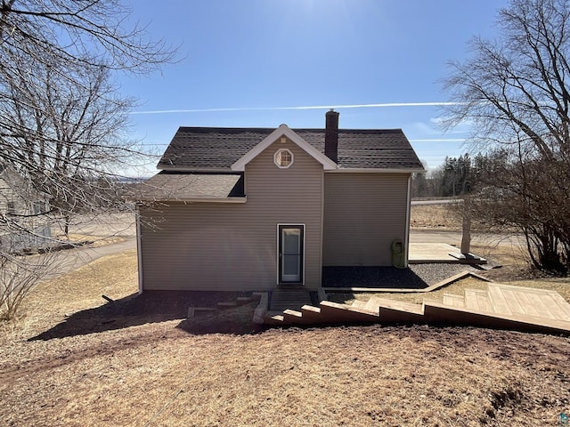 view of side of property with entry steps, a deck, and a shingled roof