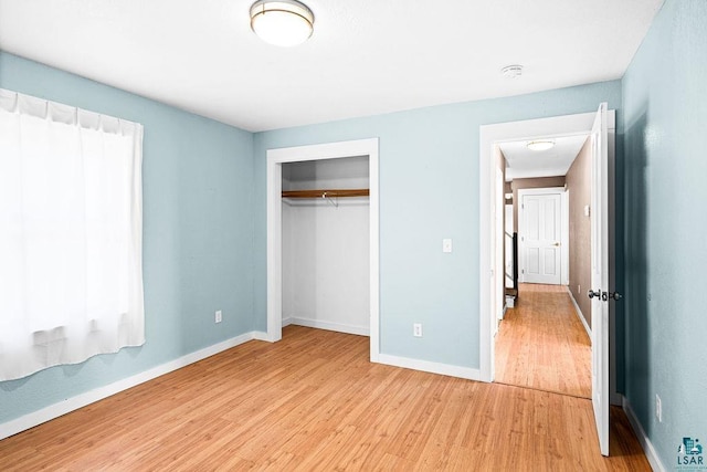 unfurnished bedroom featuring baseboards, a closet, and light wood finished floors