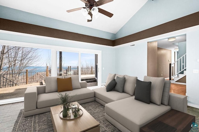 living area with stairway, a ceiling fan, baseboards, and high vaulted ceiling