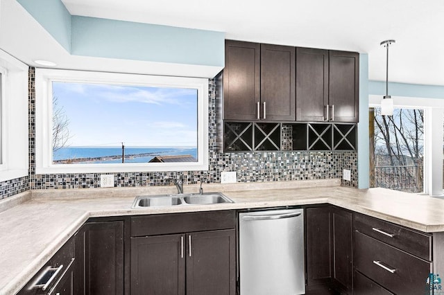 kitchen featuring a sink, dark brown cabinetry, light countertops, stainless steel dishwasher, and tasteful backsplash